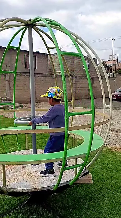 Niño jugando en el carrusel giratorio del jardín